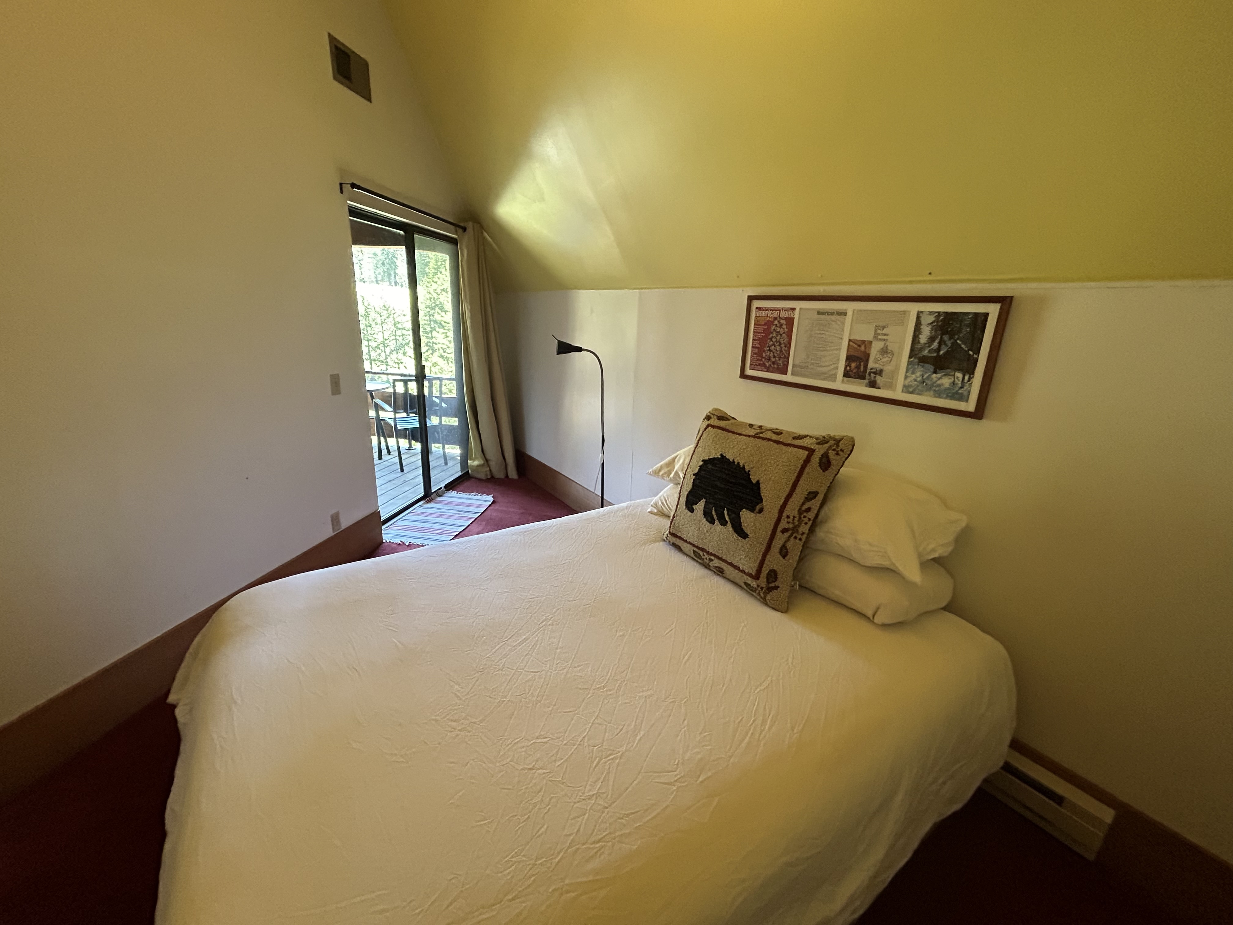 Queen bedroom with white linens and a door to the lake-facing deck
